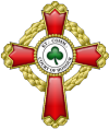 A passion cross with fancy arms with a trefoil embroidered in green in the center